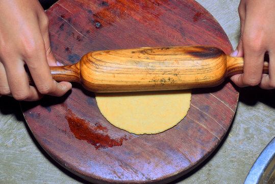 Girl hand rolling chapatis in a rural setting. kitchen concept