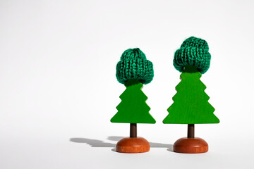 Two miniature wooden Christmas trees in knitted hats on a white background. Winter, christmas and new year concept.