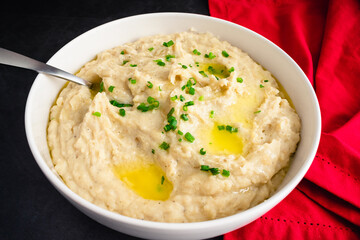 Garlic Mashed Potatoes in a Serving Bowl: A large bowl of whipped potatoes topped with chives and...