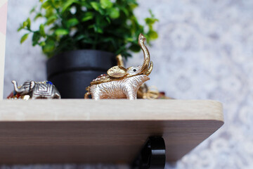 
a metal elephant figure inlaid with stones, with a raised trunk, bringing good luck. The elephant stands on a shelf in the room, an interior decoration and a symbol of abundance