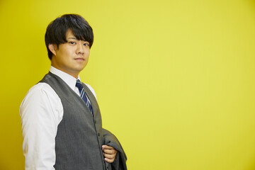 黄色背景の前でスーツを着た日本人ビジネスマンの横顔