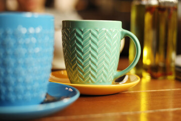 Green mug on a wooden table against a grunge background, side view of hot tea on the table in a cafe, lunch or dinner time, table setting in a restaurant