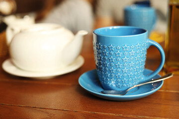 Blue mug on a wooden table against a grunge background, side view of hot tea on the table in a cafe, lunch or dinner time, table setting in a restaurant