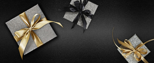 Black Friday glittering silver gift boxes wrapped with golden ribbon bow  isolated on black...