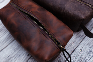 Men's personal cosmetic bag made of brown leather or a toiletry bag. Leather goods on a wooden...