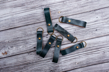 A keyring made of green leather, isolated on a wooden background. A lot of key chains made with...