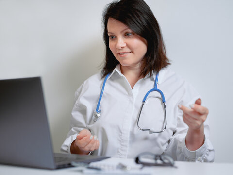 Female Doctor Consults Patient In Video Chat. A Female Medic Conducts An Online Conference On White Background. Smart Covid Consult VoIP Service App.