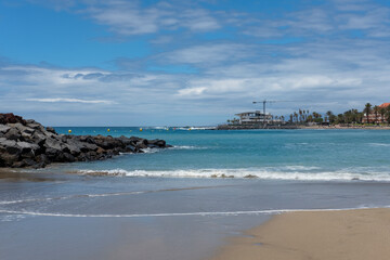 Tranquil views with partially overcast sky and little frothy waves of the popular beach located...