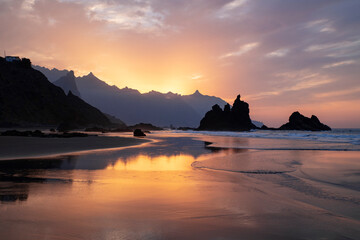 Amazing sunset with spectacular dramatic purple color sky reflecting into the water pools and the neat sand surface on the secluded Benijo beach or Playa de Benijo, in Tenerife, Canary Islands, Spain © Ana