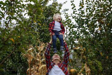 dad plays with his son on the background of the garden in the countryside