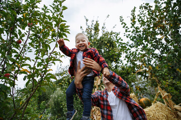 dad plays with his son on the background of the garden in the countryside