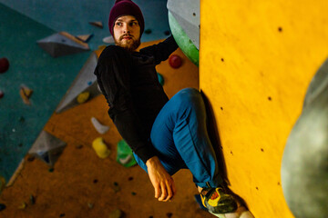 handicapped climber moving up on steep rock, climbing on artificial wall indoors