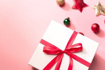 White gift box with red ribbon on pink background, christmas day present. A box for surprise in holiday.
