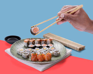 Man's hand picking up sushi with chopsticks. Japanese sushi food. Roll sushi set
