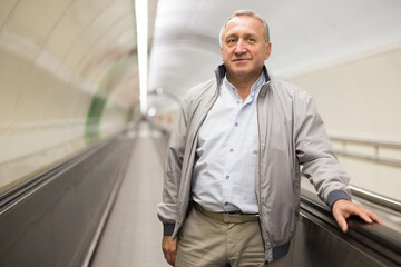 Fototapeta premium Senior passenger walks along travelator in an underground metro