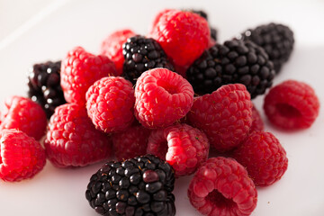 handful of raspberry and blackberry berries on white background