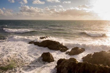 Fototapeta na wymiar Waves crash along Bodega Bay in northern California at sunset.