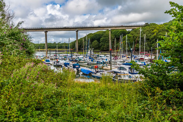 Fototapeta na wymiar A tree framed view of Westfield Pill showing boats moored and the road bridge at Neyland, Pembrokeshire, South Wales on a summers day