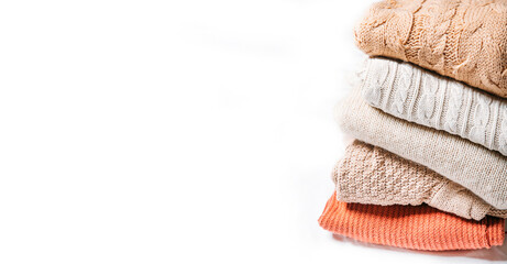 warm sweaters stacked on a white background 