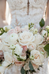 Bride holding a bouquet of white and pink roses outside Cropped view Close up Blooming Flowers in Detail on the background of the bride's white dress fresh flowers Wedding concept