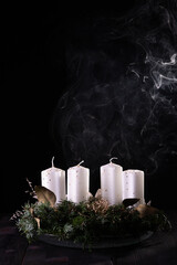 First Advent - Advent wreath from fir and evergreen branches with blown out candle on dark wooden...