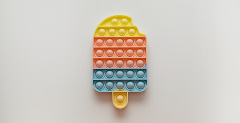 Colorful trendy Pop it fidgets ice cream shape toy on a bright grey background.