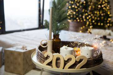 wooden numbers 2022, cups with marshmellow and sweets on the background of Christmas decor
