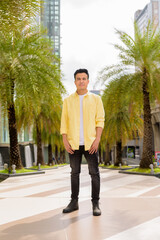 Full length portrait of handsome young man outdoors in city during summer