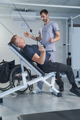 Fototapeta na wymiar Patient with injury doing strength exercises with physiotherapist help