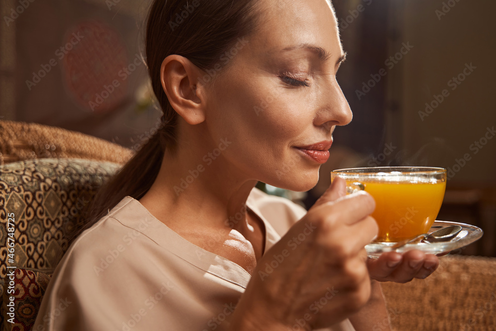 Wall mural Calm woman enjoying flavor of her herbal beverage