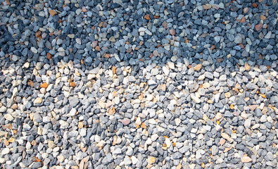 Light and shadow patterns on space of white, gray, black pebble wall.