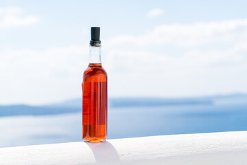 A bottle of red wine on a white wall against the background of the sea in the Greek village of Oia