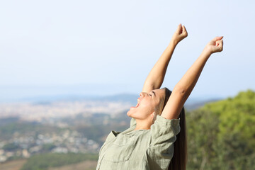 Excited teen celebrating raising arms outdoors
