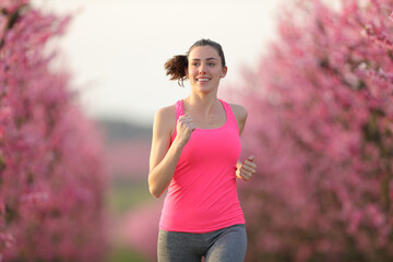 Front view of happy runner running in a pink field