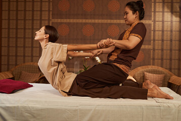 Practitioner doing kneeling assisted Cobra spinal stretch