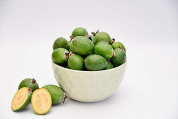A bowl of green feijoa on the white background in the middle of photo. Horizontal view.