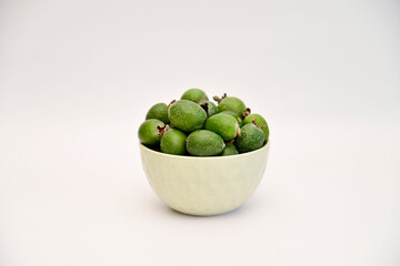 A bowl of green feijoa on the white background in the middle of photo. Horizontal view.