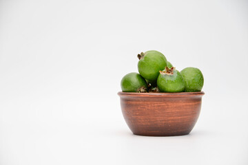 A bowl of green feijoa on the white background on the right of side. Horizontal view.