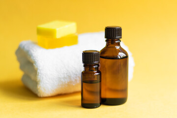 2 jars of brown glass with oil, soap, white towel lie on a yellow background