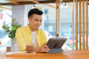 Young man at coffee shop using digital tablet computer