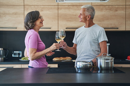 Married senior couple drinking champagne in the kitchen