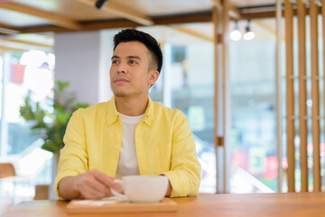 Portrait of handsome young man at coffee shop thinking
