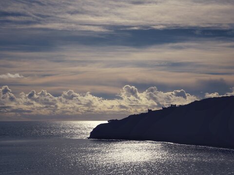 landscape silhouette of cliff with sea reflecting the sun