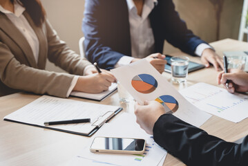 Close up hands of a businessman holding graph paperwork on the meeting conference table.