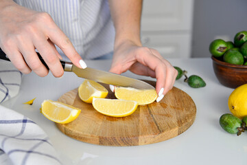 woman hands is cutting lemon on wooden.