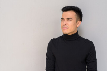 Portrait of handsome young man thinking against gray background