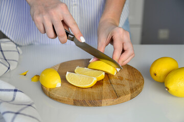 woman hands are cutting lemons on wooden board. horizontal view.
