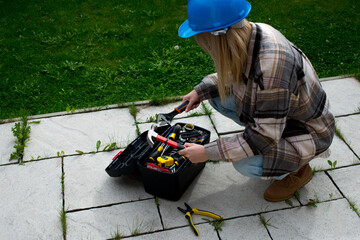 Woman in a helmet with tools. A blond woman is building a house. Female worker. Destroying gender...