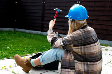 Woman in a helmet with tools. A blond woman is building a house. Female worker. Destroying gender...