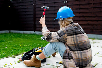 Woman in a helmet with tools. A blond woman is building a house. Female worker. Destroying gender...
